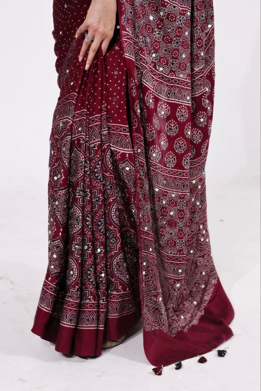 Maroon Ajrakh Print Mirror Work Saree With Designer Border & Tassels With Matching Blouse Piece